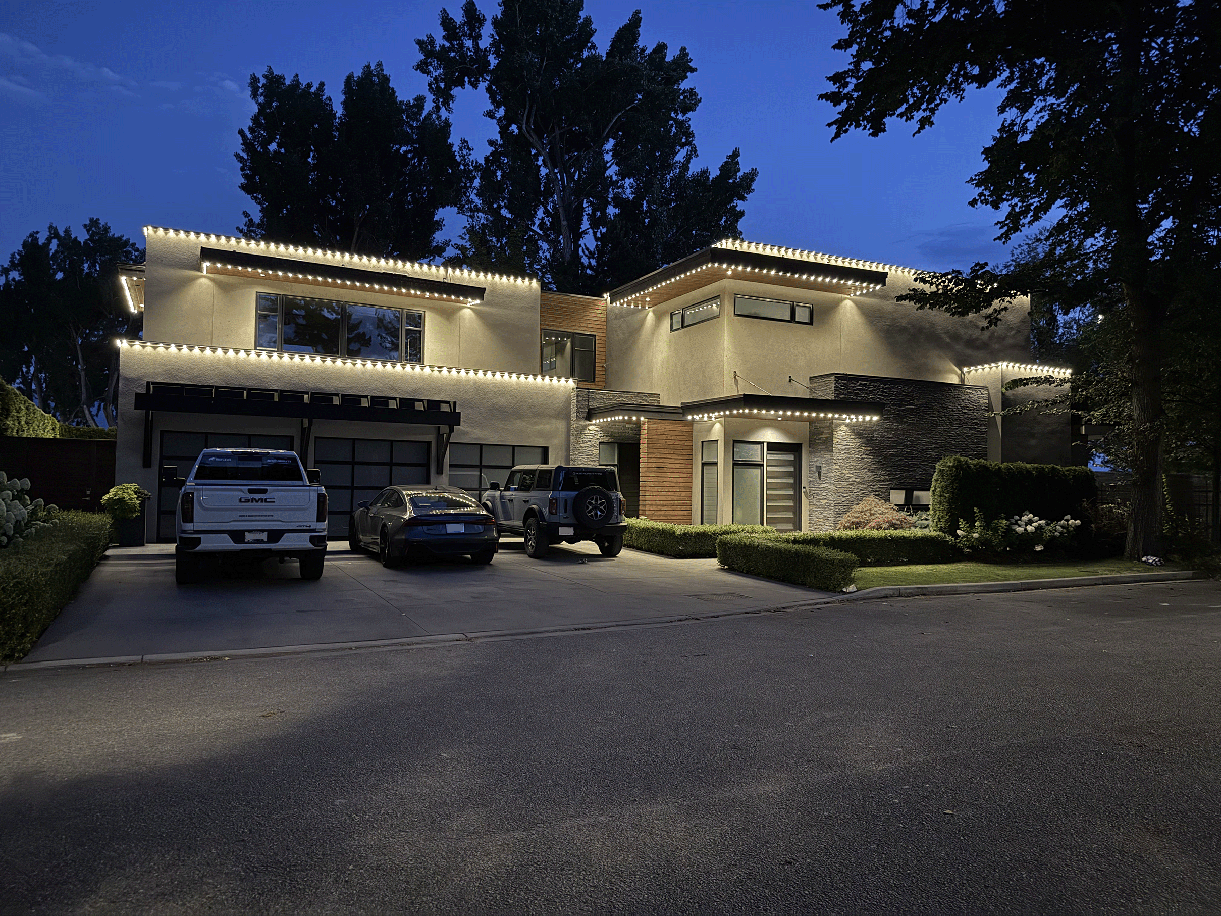 Luxury modern home with permanent outdoor LED track lighting in pure white, installed by Perma-Lights. Energy-efficient RGBW system highlighting architectural features
